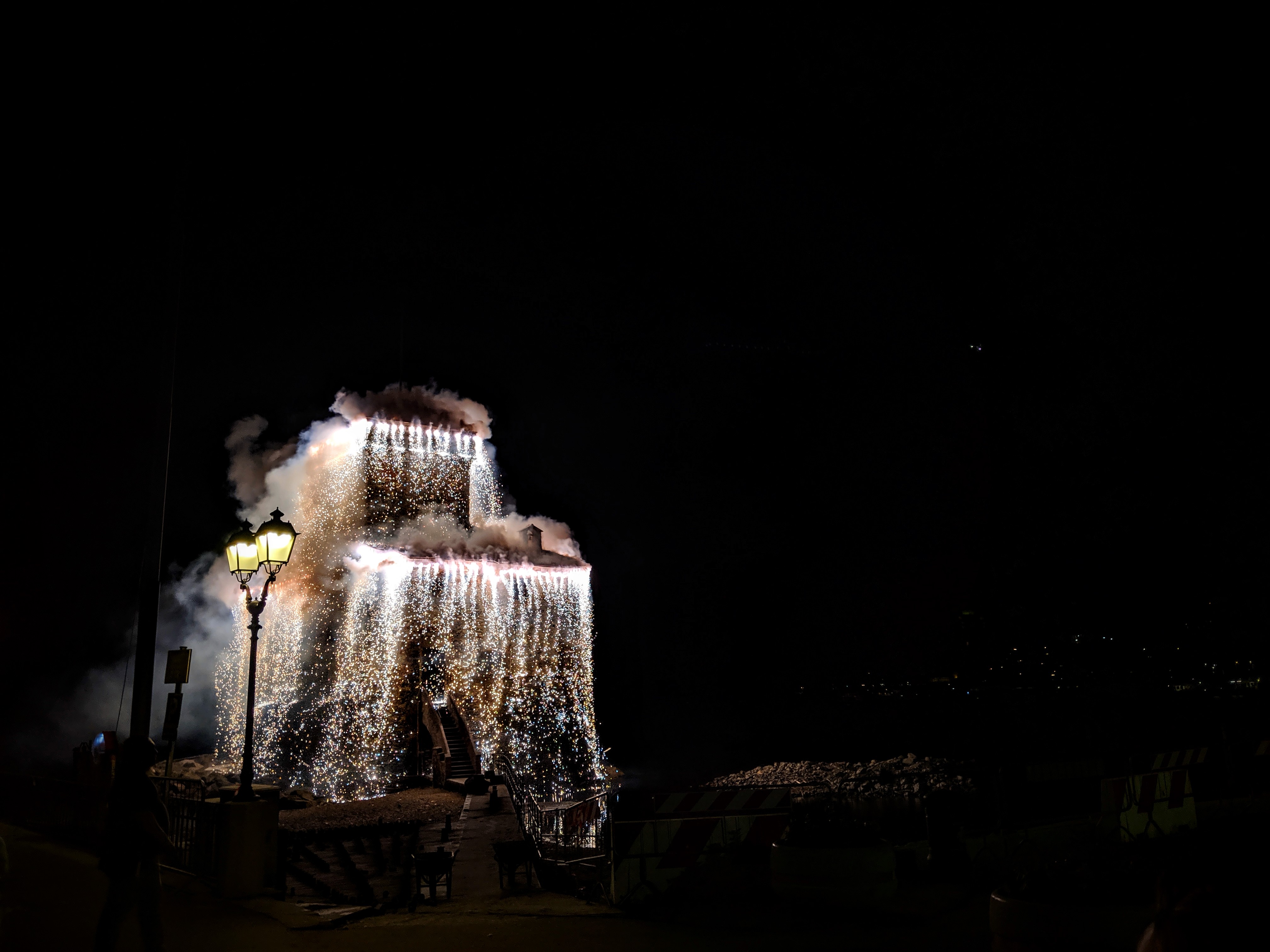 Rapallo's old fortress with flames dripping down from it.