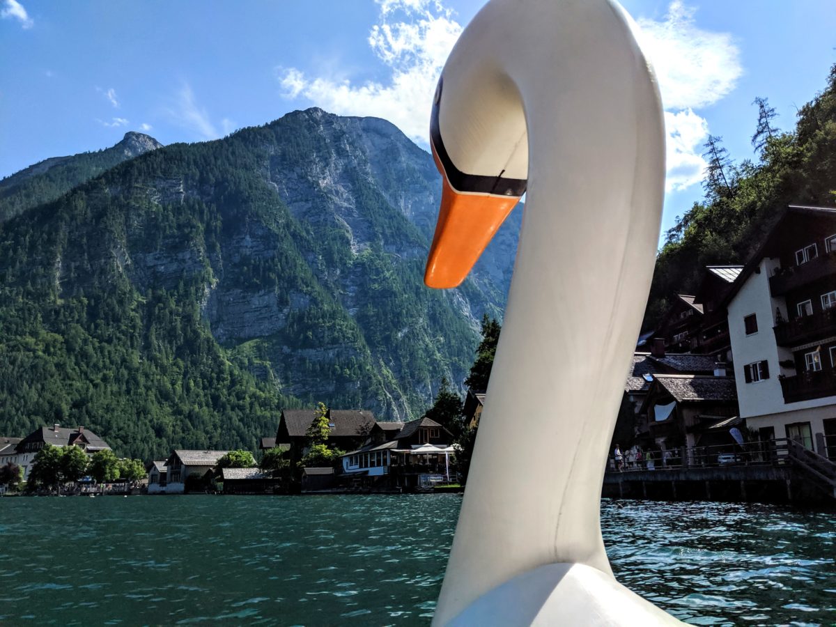 A swan paddle boat with mountains around.