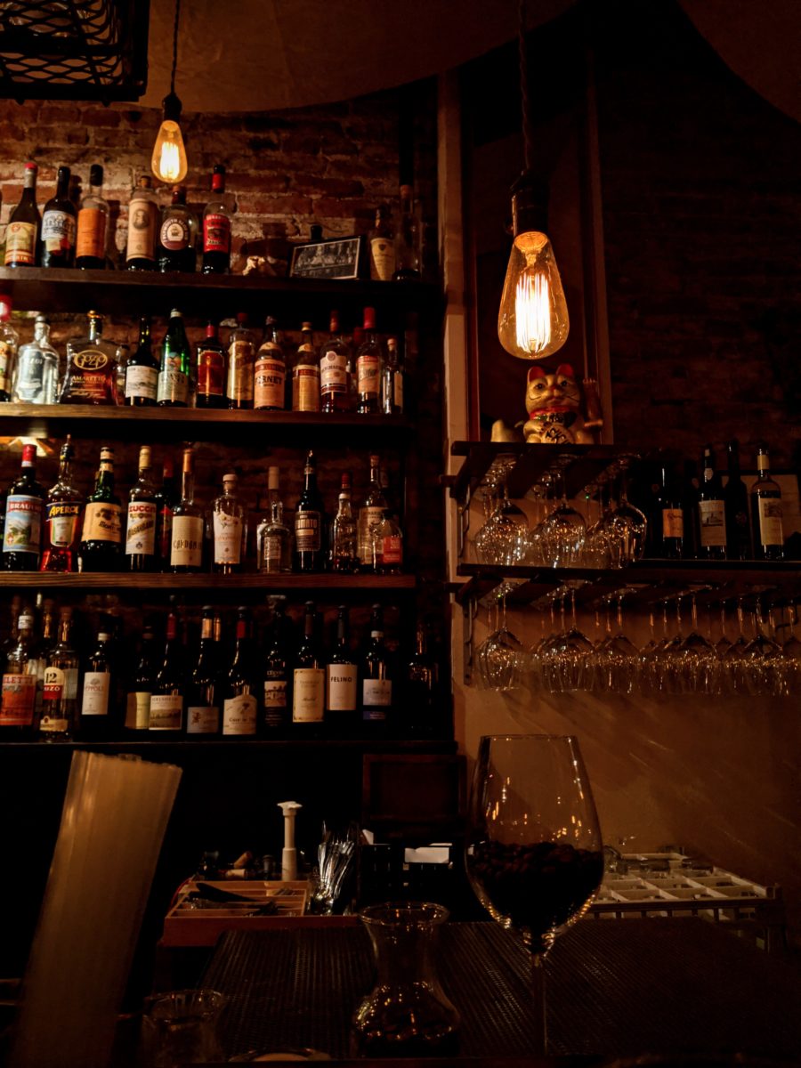 A bar with liquor bottles on a shelf against the wall.